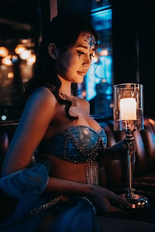 Young Woman Wearing Ornate Clothing Holding a Burning Candlestick Holder