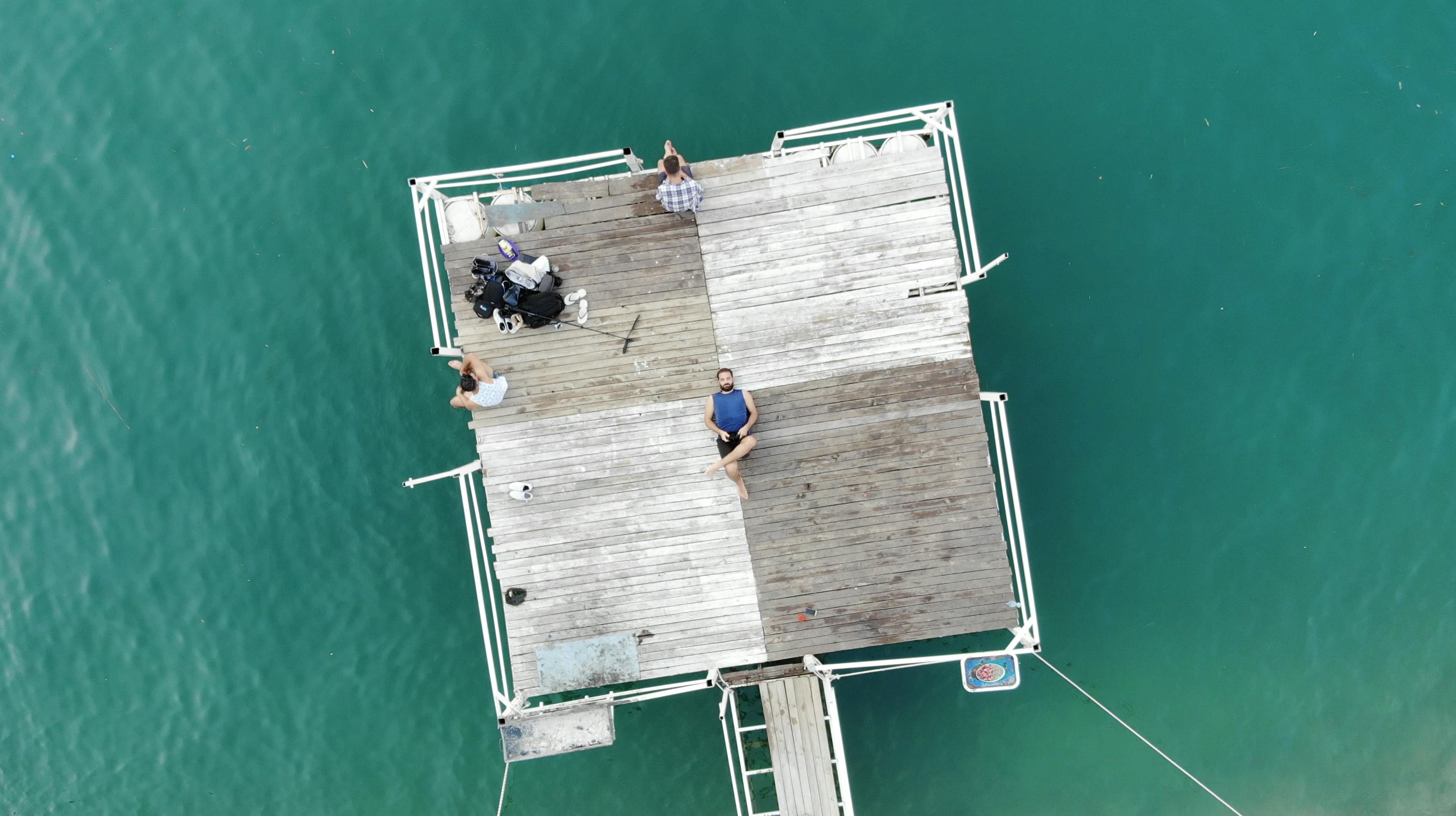 一群人在碧绿水面的木码头上享受休闲时光