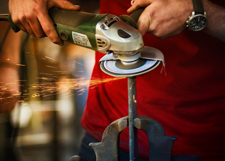 Close-up of a worker using an angle grinder with sparks flying, showcasing precision and craftsmanship.