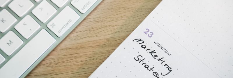 Close-up of a desk with a keyboard and a calendar open to a marketing strategy note.