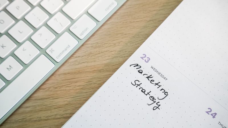 Close-up of a desk with a keyboard and a calendar open to a marketing strategy note.