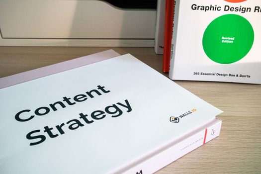 Books on content strategy and graphic design essentials resting on a wooden desk.