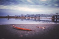 一座钢桥横跨在平静的河面上，倒映着多云的天空，拍摄于宁静的户外环境中