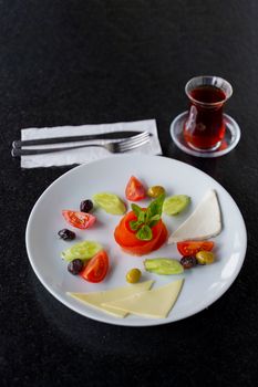 A beautifully arranged Mediterranean antipasti platter with fresh vegetables, cheese, and tea.