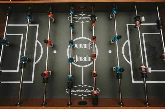 Top view of a foosball table with blue and red players, ready for play.