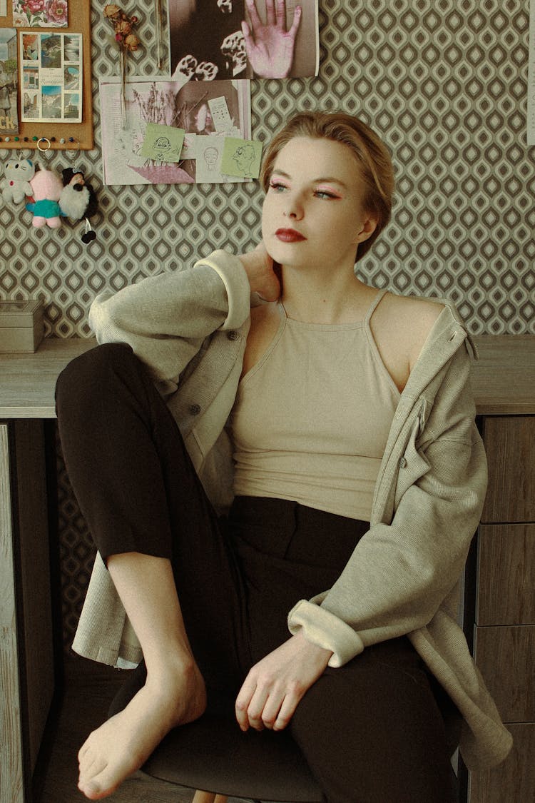 Barefoot Woman Sitting On Couch Under Wall Decorated With Photographs