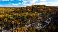 明亮的天空下，五颜六色的秋天森林和悬崖构成了一幅迷人的鸟瞰图
