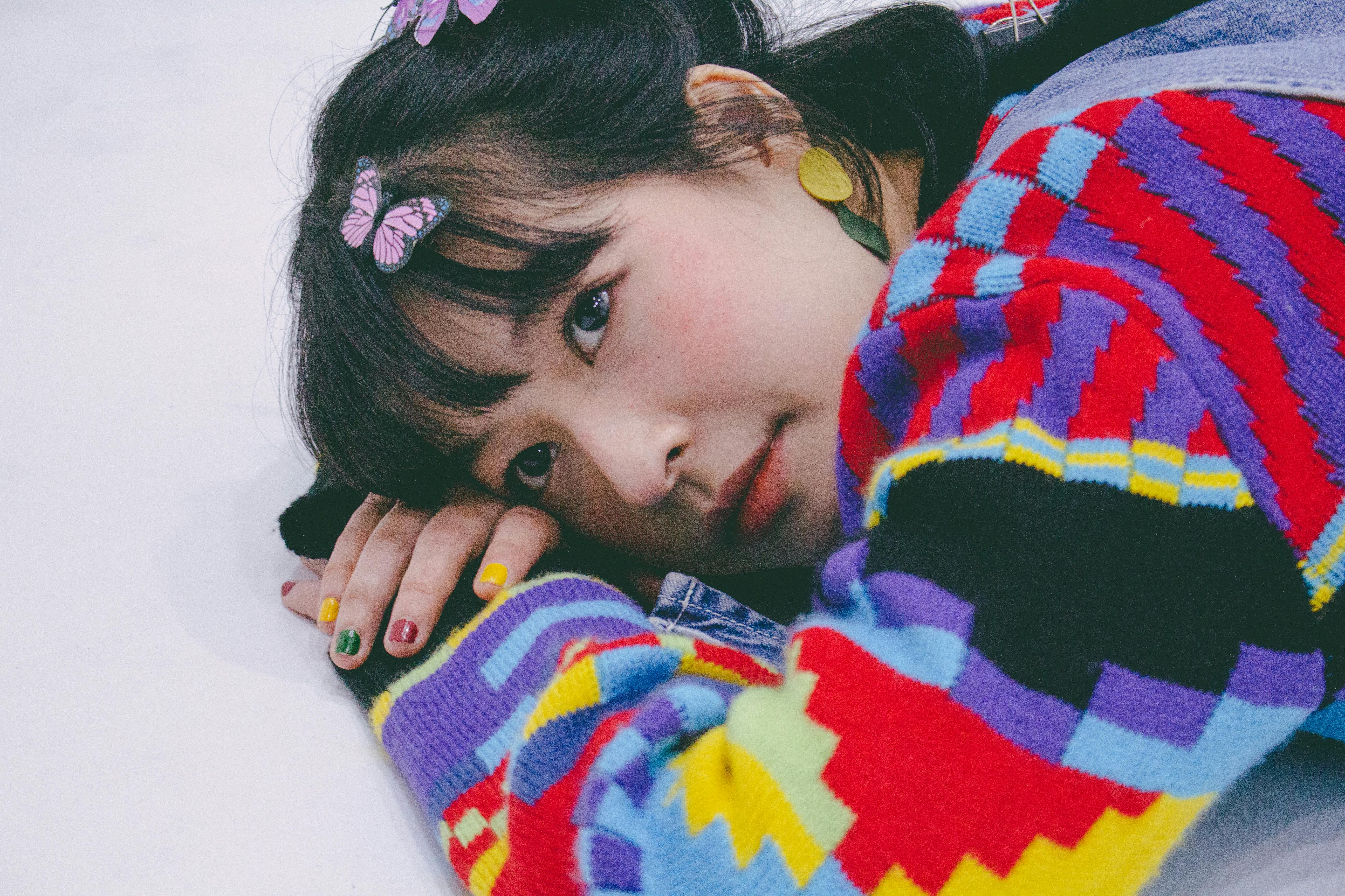 Portrait of woman with colorful sweater and butterfly clips, lying down.