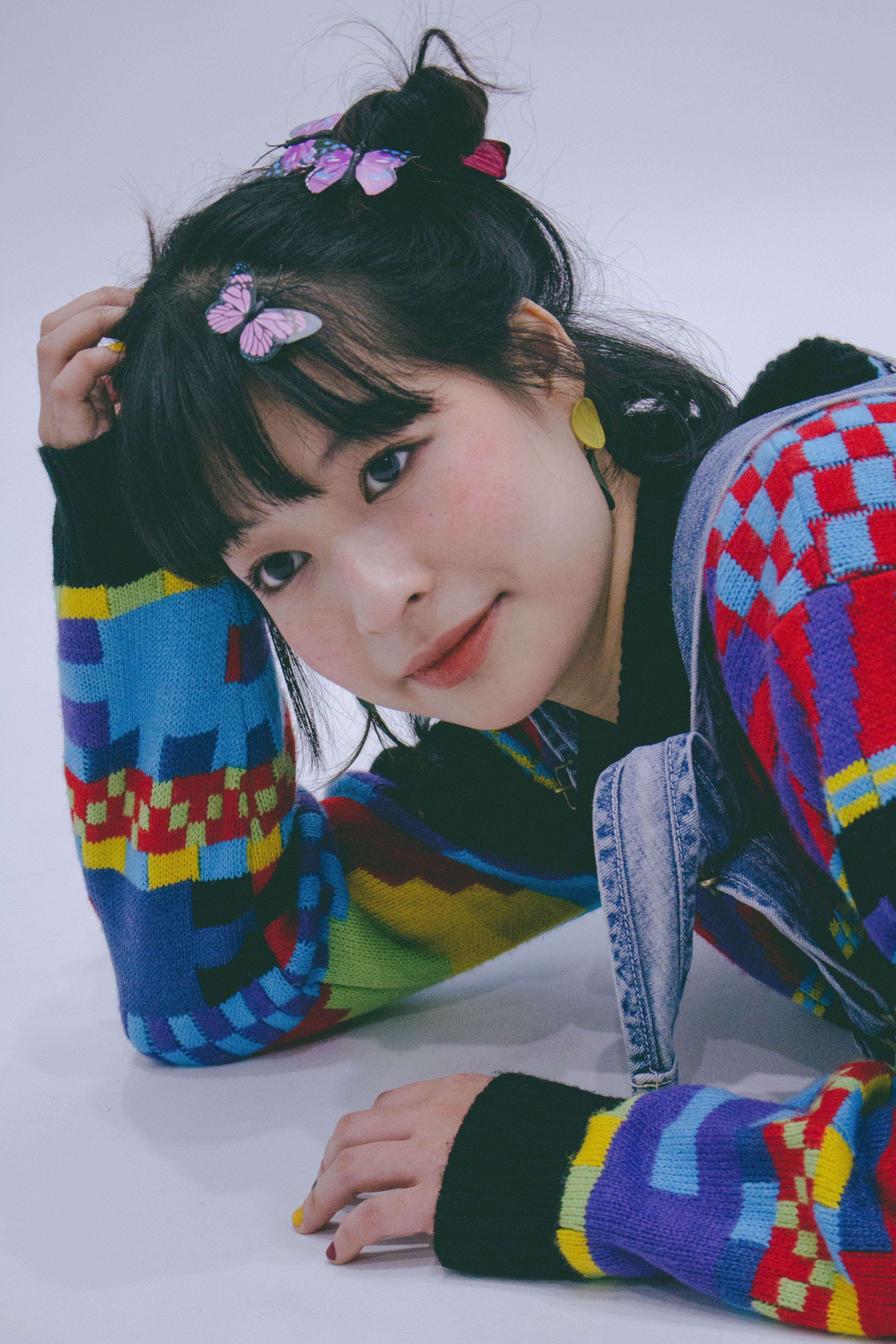 Vibrant portrait of a woman smiling in a multi-colored sweater with butterfly hair accessories.