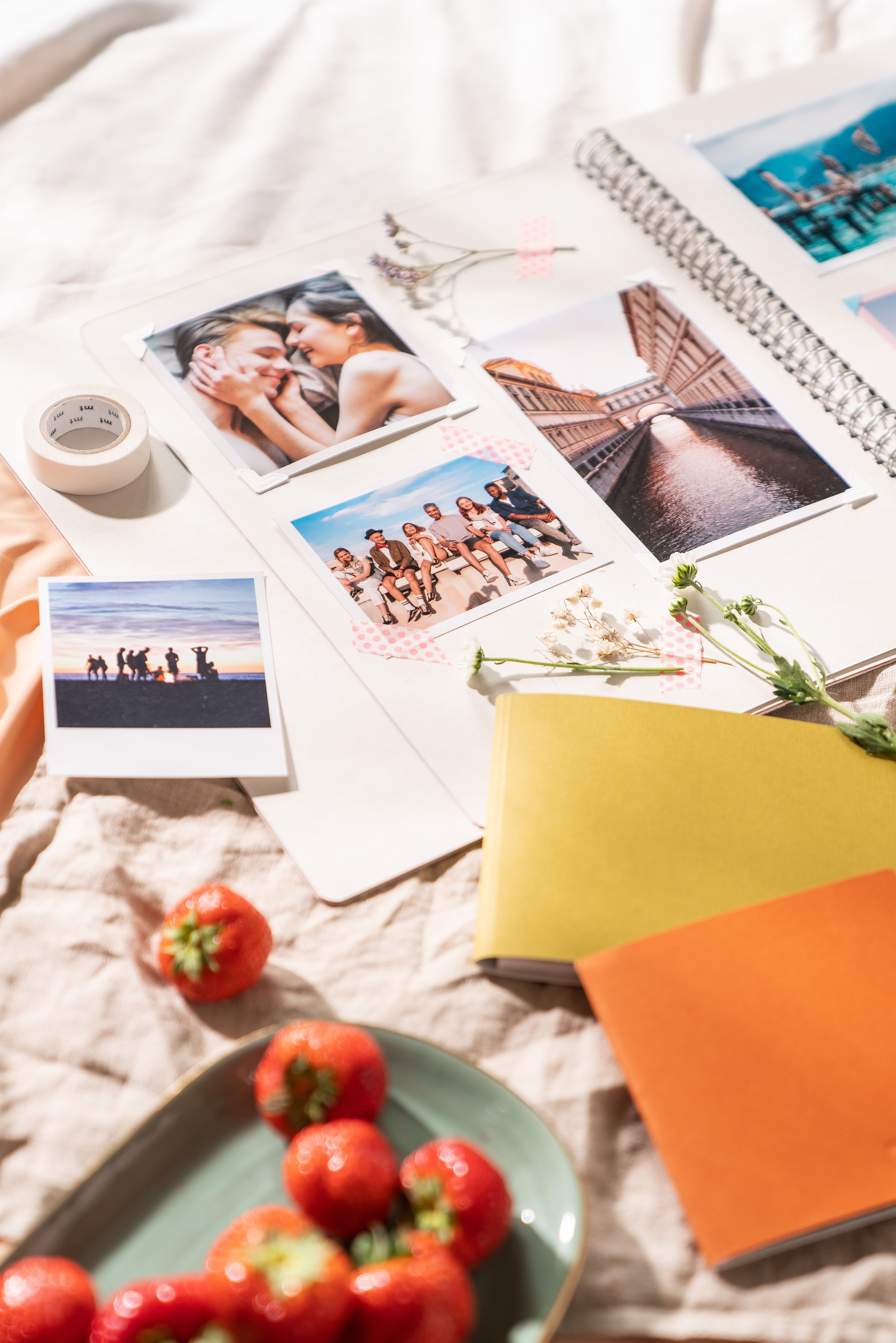 A vibrant spread of a photo album with prints, tomatoes, and sunlight creating a warm atmosphere.