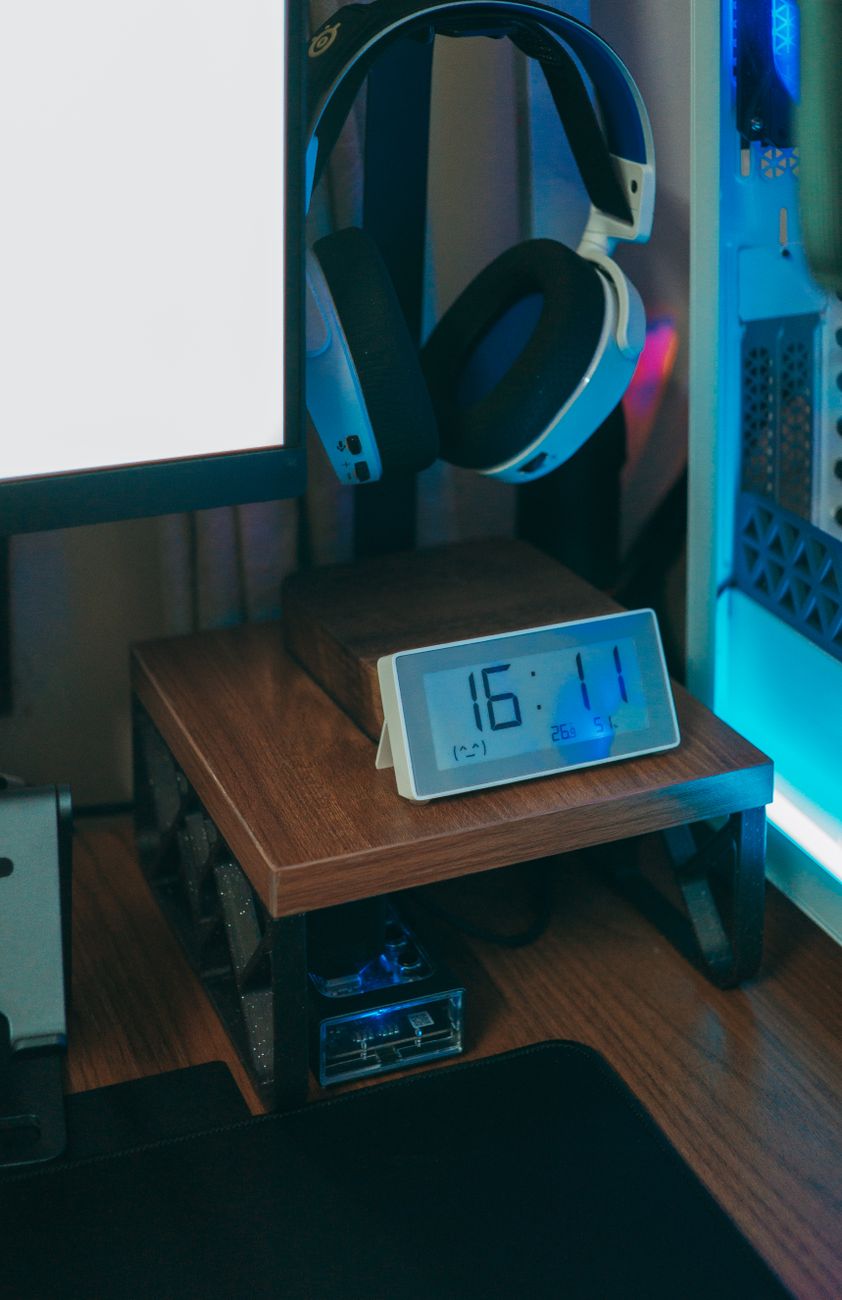 Close-up of a stylish desk setup featuring a digital clock and headphones, showcasing technology integration in a home office.