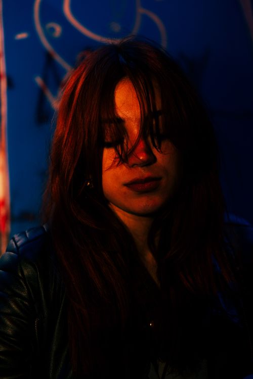 Free Dramatic portrait capturing a woman with closed eyes and red hair against a dark background. Stock Photo
