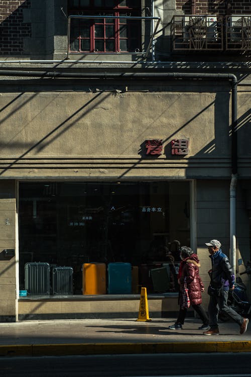 People Walking past Window Displaying Suitcases