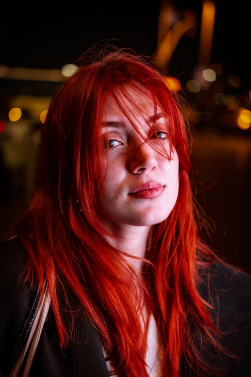 Free Close-up of a red-haired woman with a focused expression in a night setting. Stock Photo