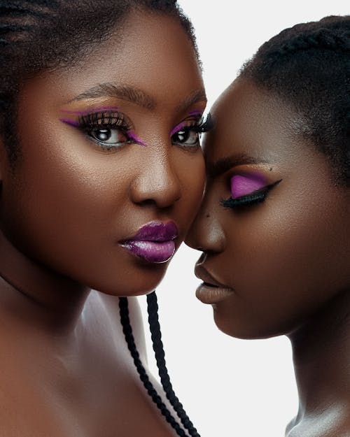 Two Women Wearing Makeup with Purple Eyeshadow Posing in Studio 