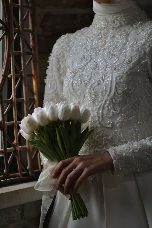 Photo of a Bride in a Wedding Dress Holding a Bouquet of White Tulips