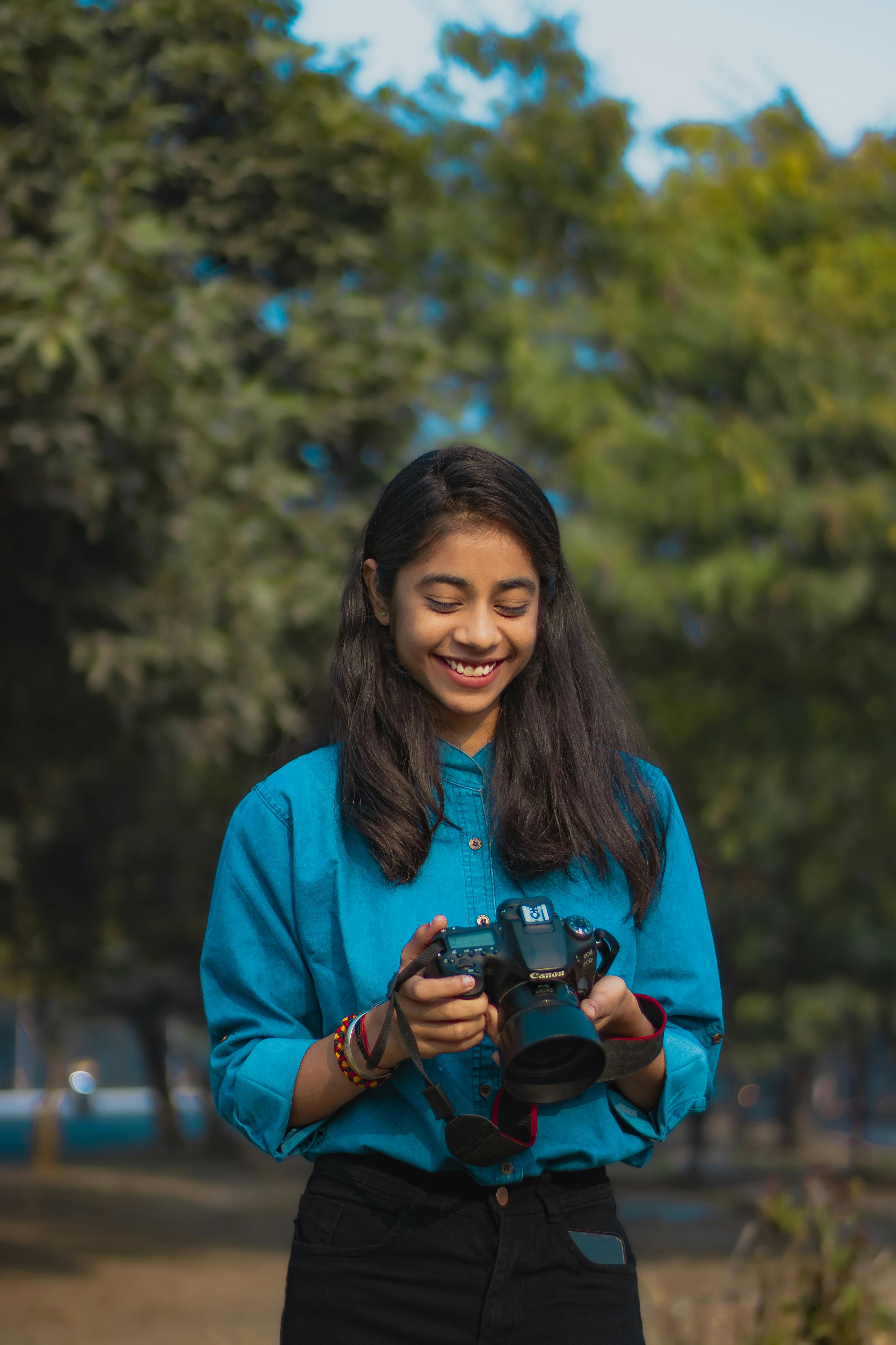 smiling-young-woman-with-camera-in-hands-free-stock-photo