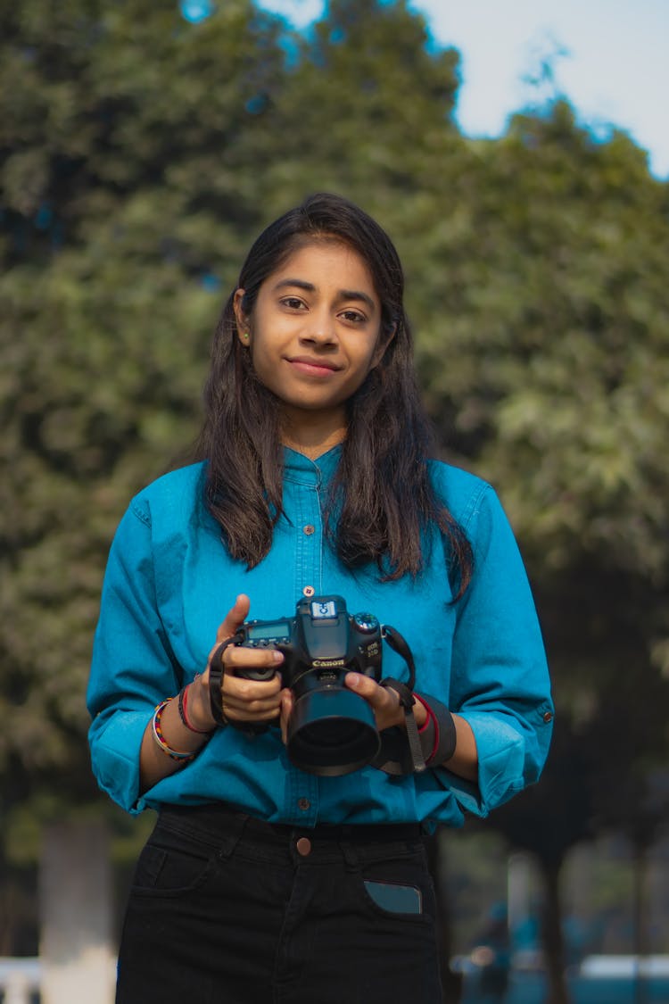 Young Girl Standing Outside And Holding A Camera 