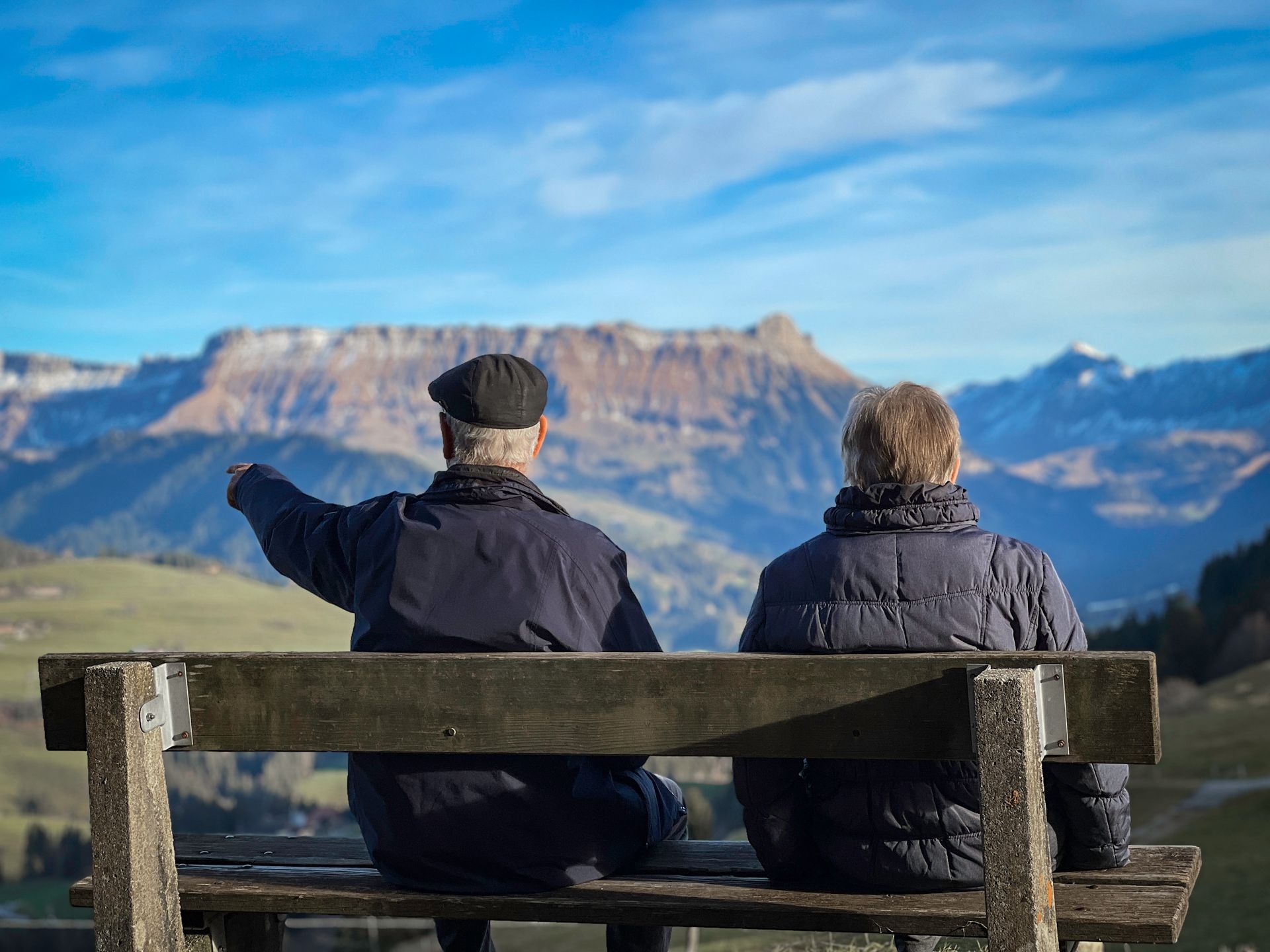 Senior couple sits on bench admiring Swiss Alps landscape in Lucerne.