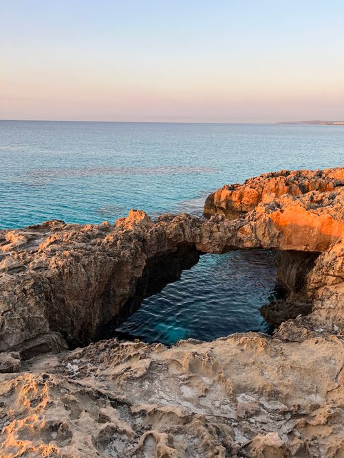 Free Stunning sunrise view of a natural rock arch over the sea in Larnaca, Cyprus. Stock Photo
