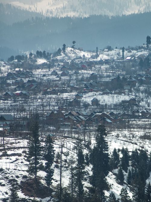 Free Winter aerial view of a snow-covered village near Srinagar with distant mountains. Stock Photo
