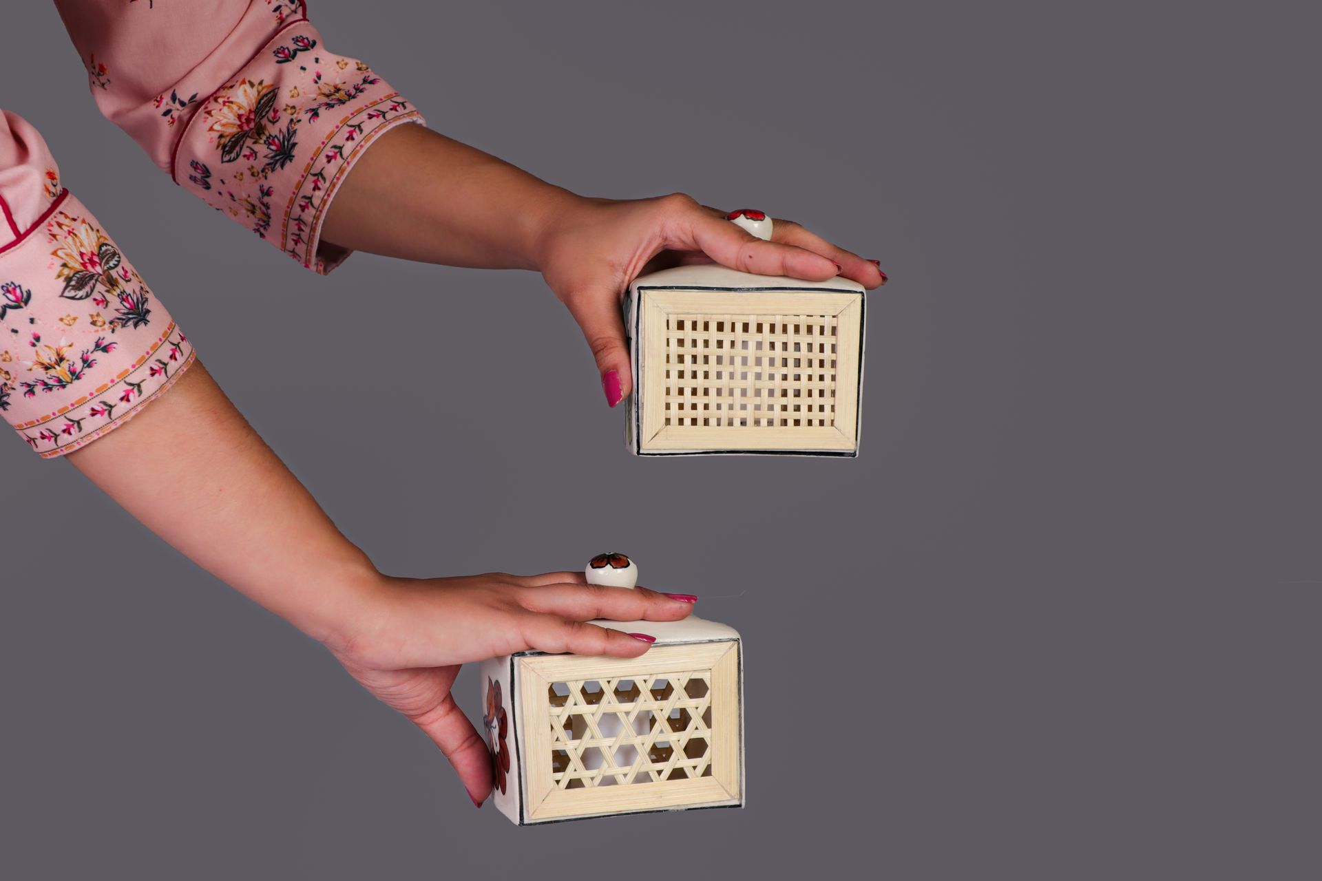 A beautifully adorned hand showcasing a set of handcrafted jewelry boxes with intricate designs.