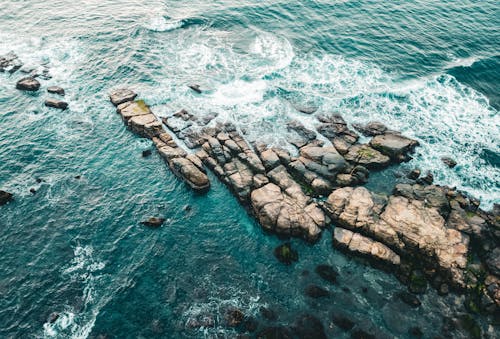 Aerial View of Water Splashing on a Rocky Shore 