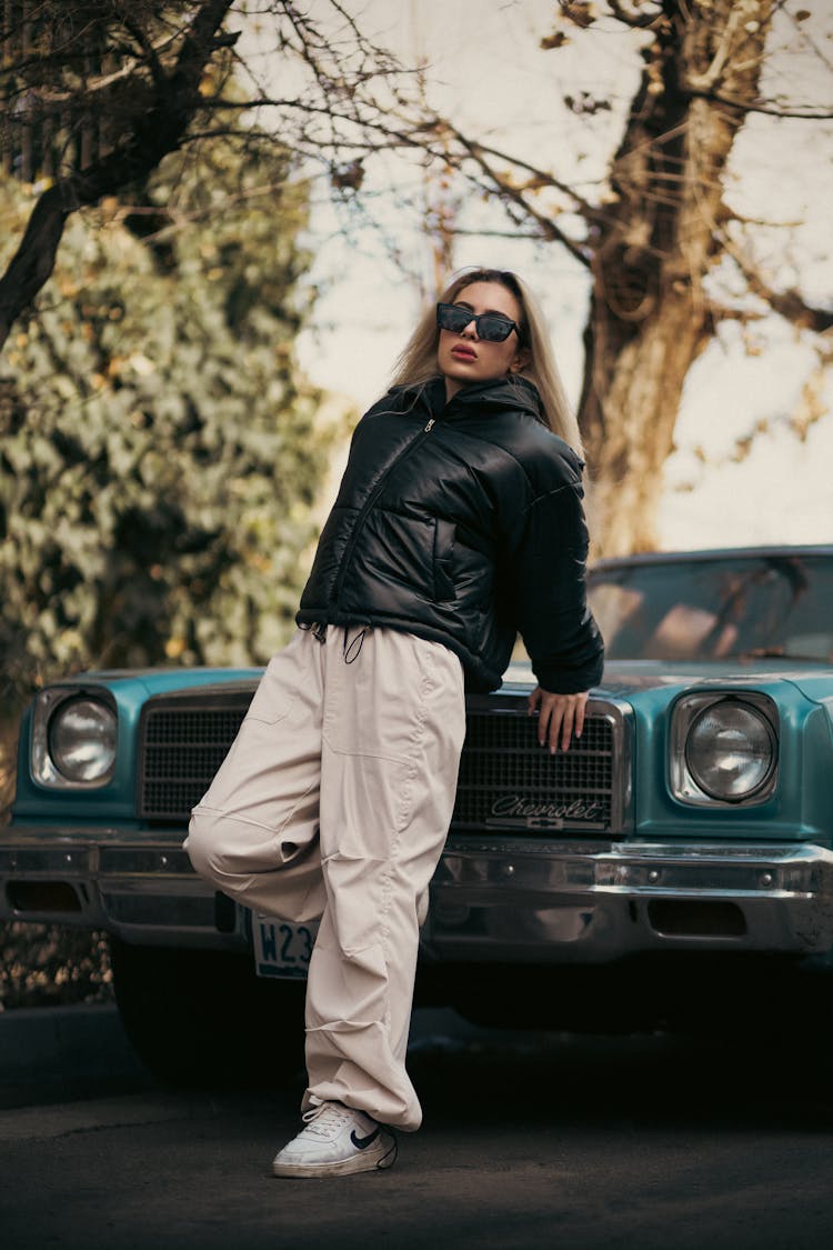 Woman In Puffer Jacket Posing By Classic Car