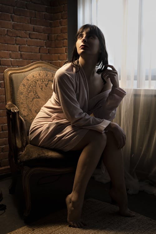 Young Woman in a Pink Bathrobe Sitting on an Antique Armchair