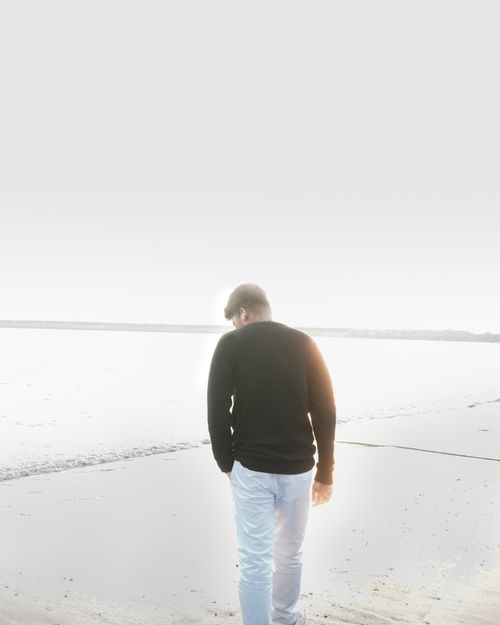 Free Solitary man walks along the serene Kozhikode beach under bright sunlight. Stock Photo