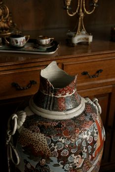 A vintage Chinese porcelain vase with intricate designs, broken at the neck. — photo by Beyzaa Yurtkuran