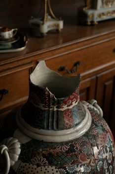 A broken antique vase with oriental pattern in a dimly lit museum setting for artistic appeal. — photo by Beyzaa Yurtkuran