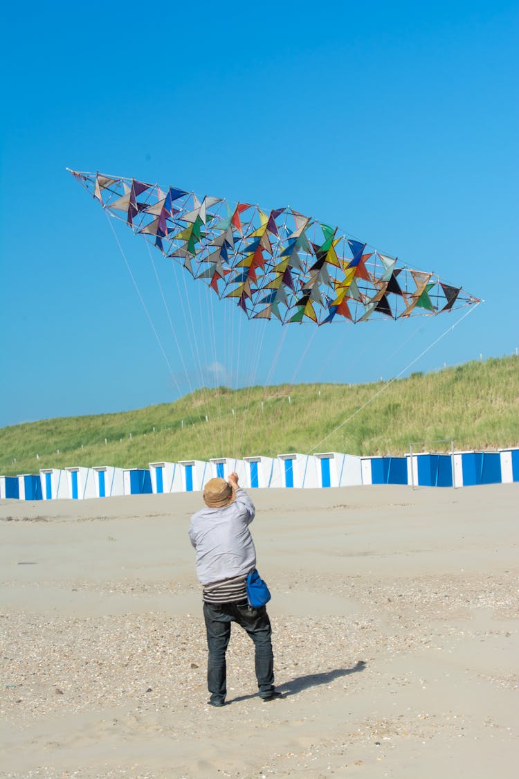 Man Flying With Kite On Sand Beach