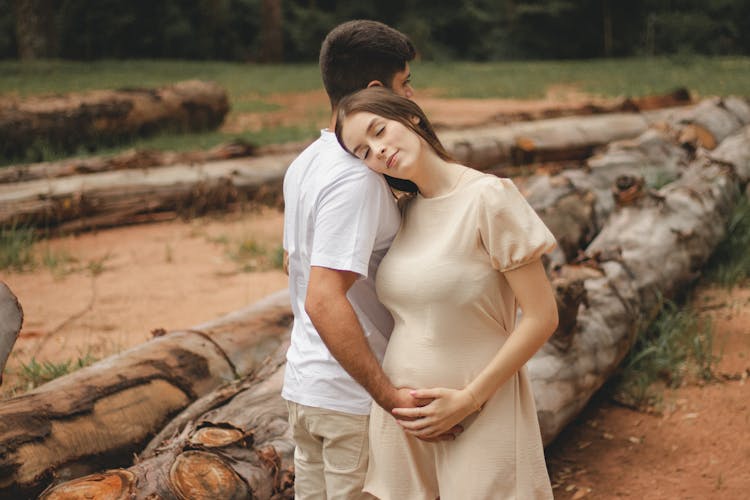 Man Hugging Pregnant Woman In Nature