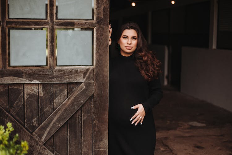 Pregnant Woman Standing Near Wooden Doors