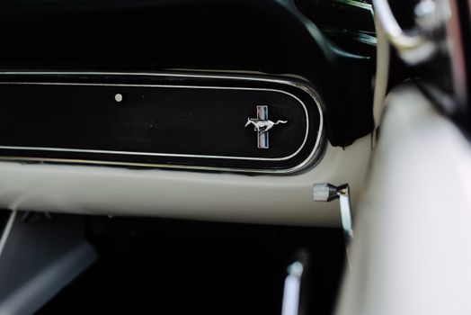 Detailed view of the Ford Mustang logo on a vintage car's dashboard. 15640931