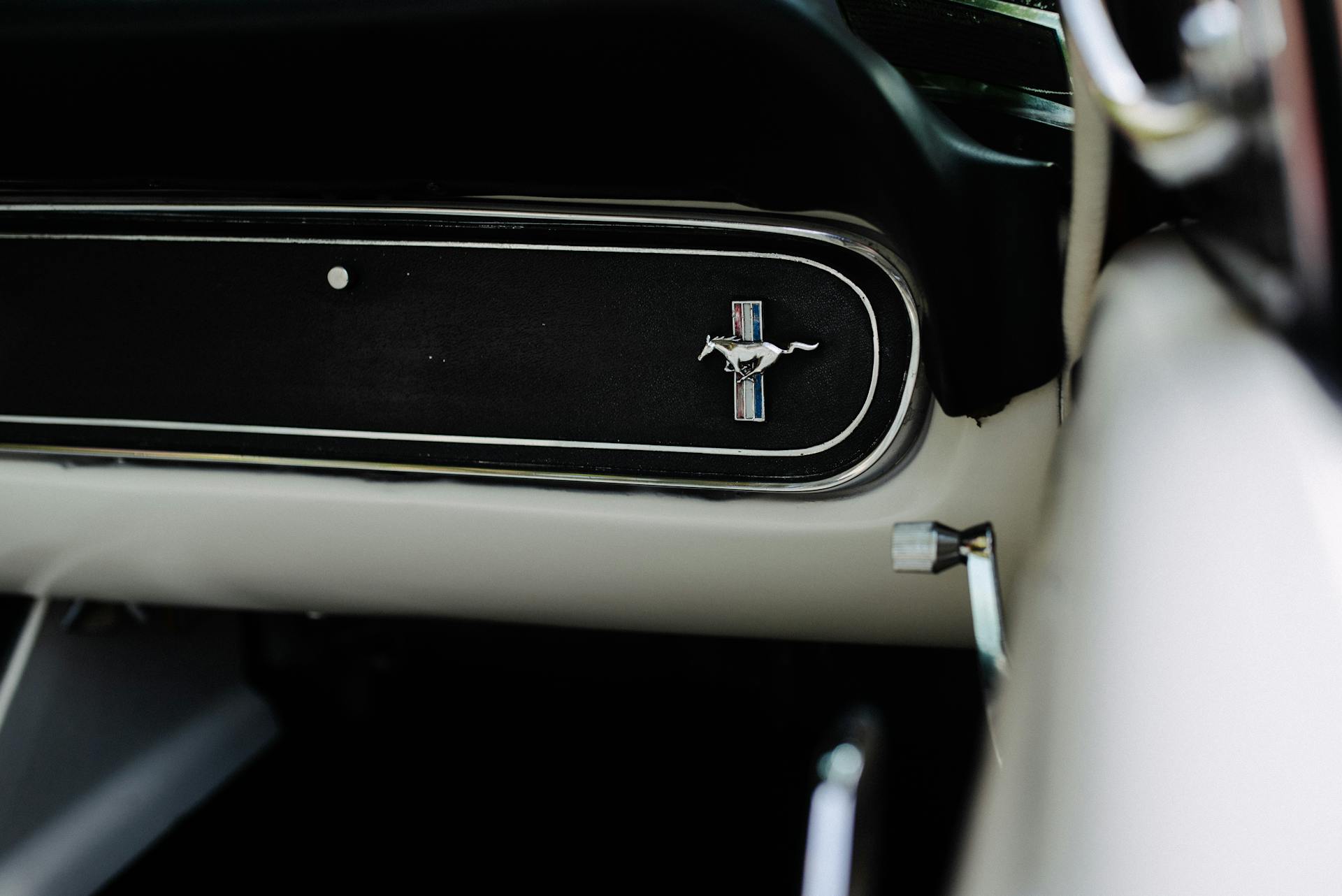 Detailed view of the Ford Mustang logo on a vintage car's dashboard.