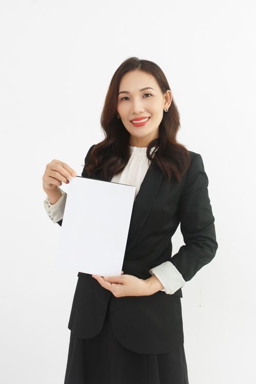 Free Smiling businesswoman in suit holding a blank document with copy space. Stock Photo