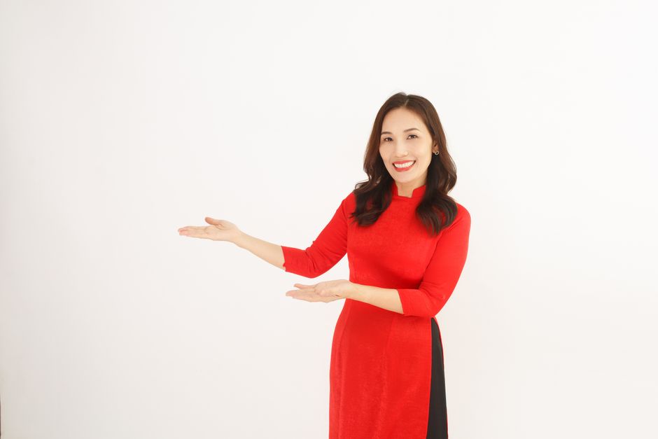 Confident businesswoman in a red dress pointing to copy space, ideal for presentations.