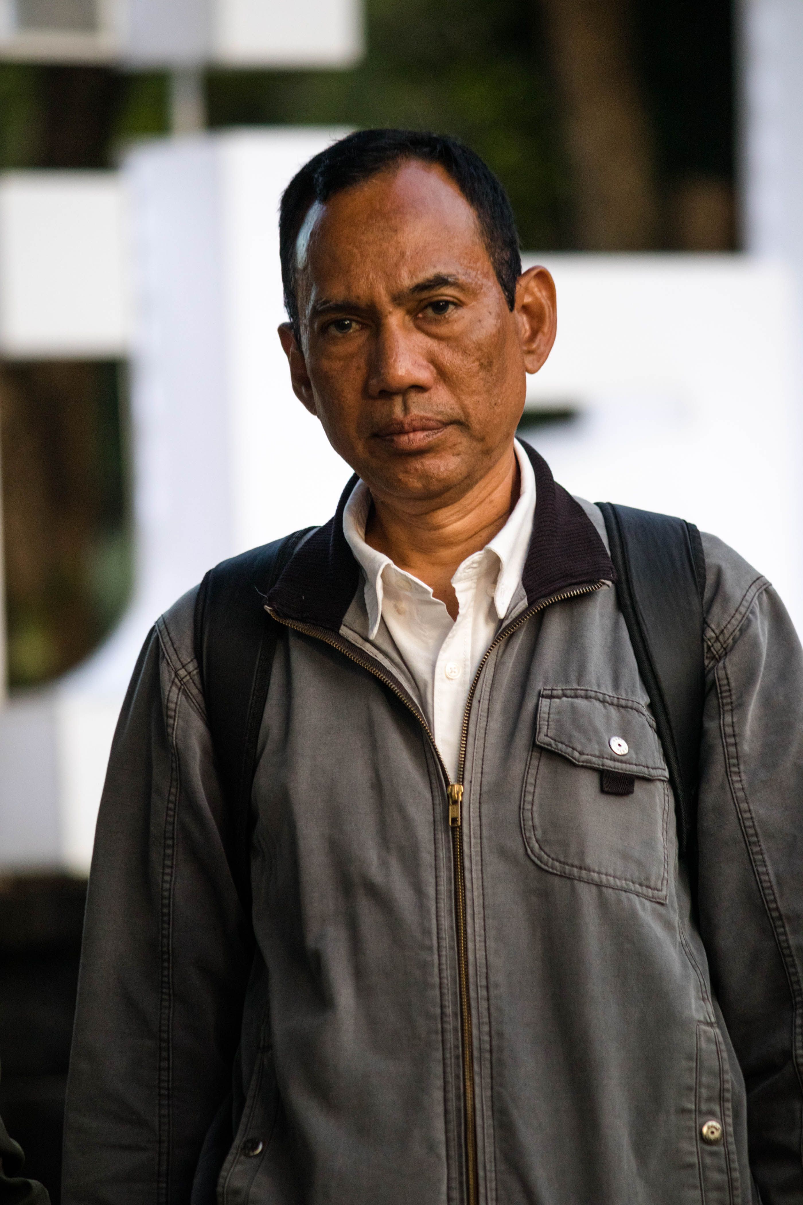 Portrait of a serious man in a jacket standing outdoors, showcasing street fashion.