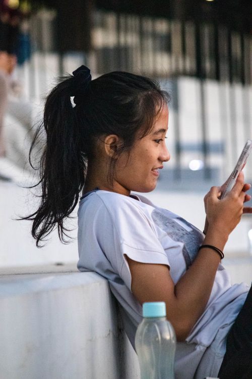 Free Casual young woman enjoying her smartphone outdoors on a sunny day. Stock Photo