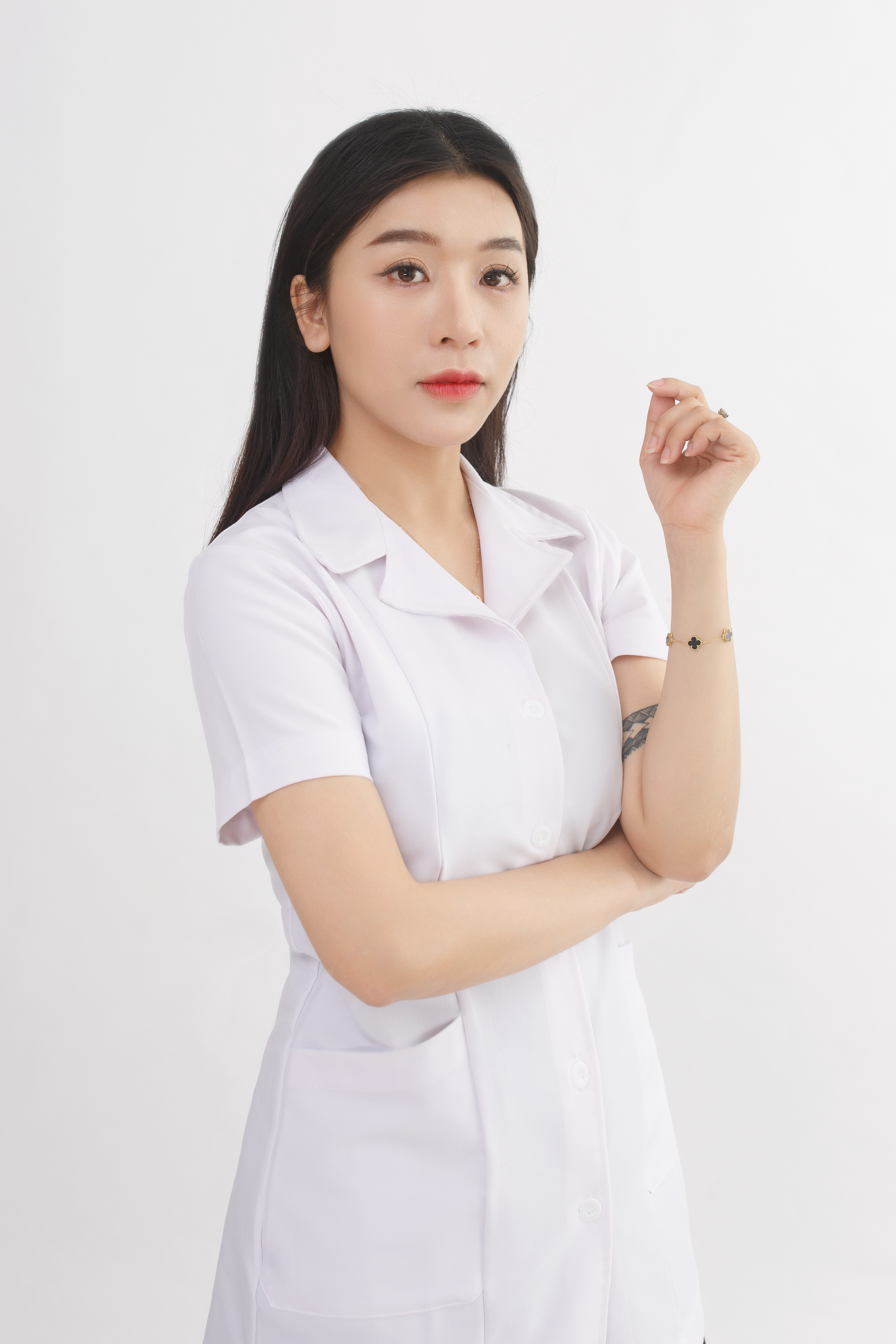 Portrait of a young nurse in a white uniform against a bright background.