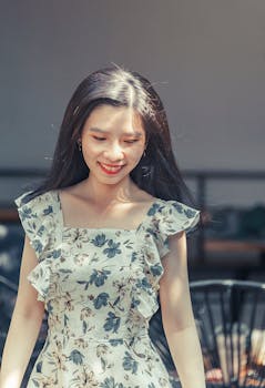 Portrait of a beautiful young woman in a floral dress enjoying a sunny day outdoors.