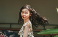 一位长发飘逸的亚洲女性，在户外微笑着享受阳光明媚的一天