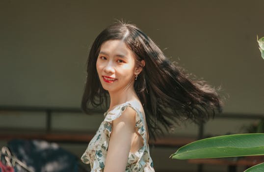 一位长发飘逸的亚洲女性，在户外微笑着享受阳光明媚的一天