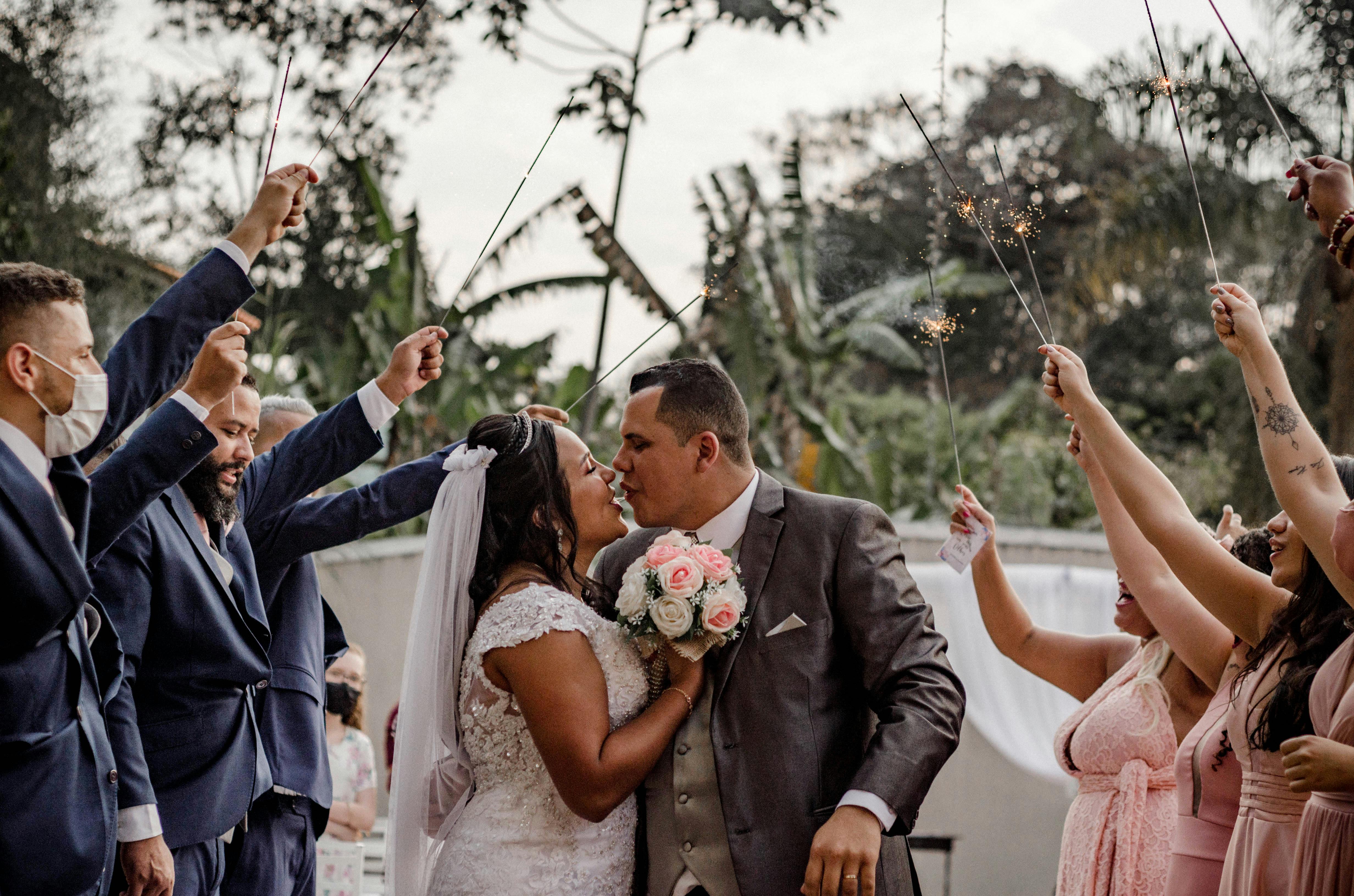Bride and groom share a romantic kiss under a sparkling send-off outdoors.