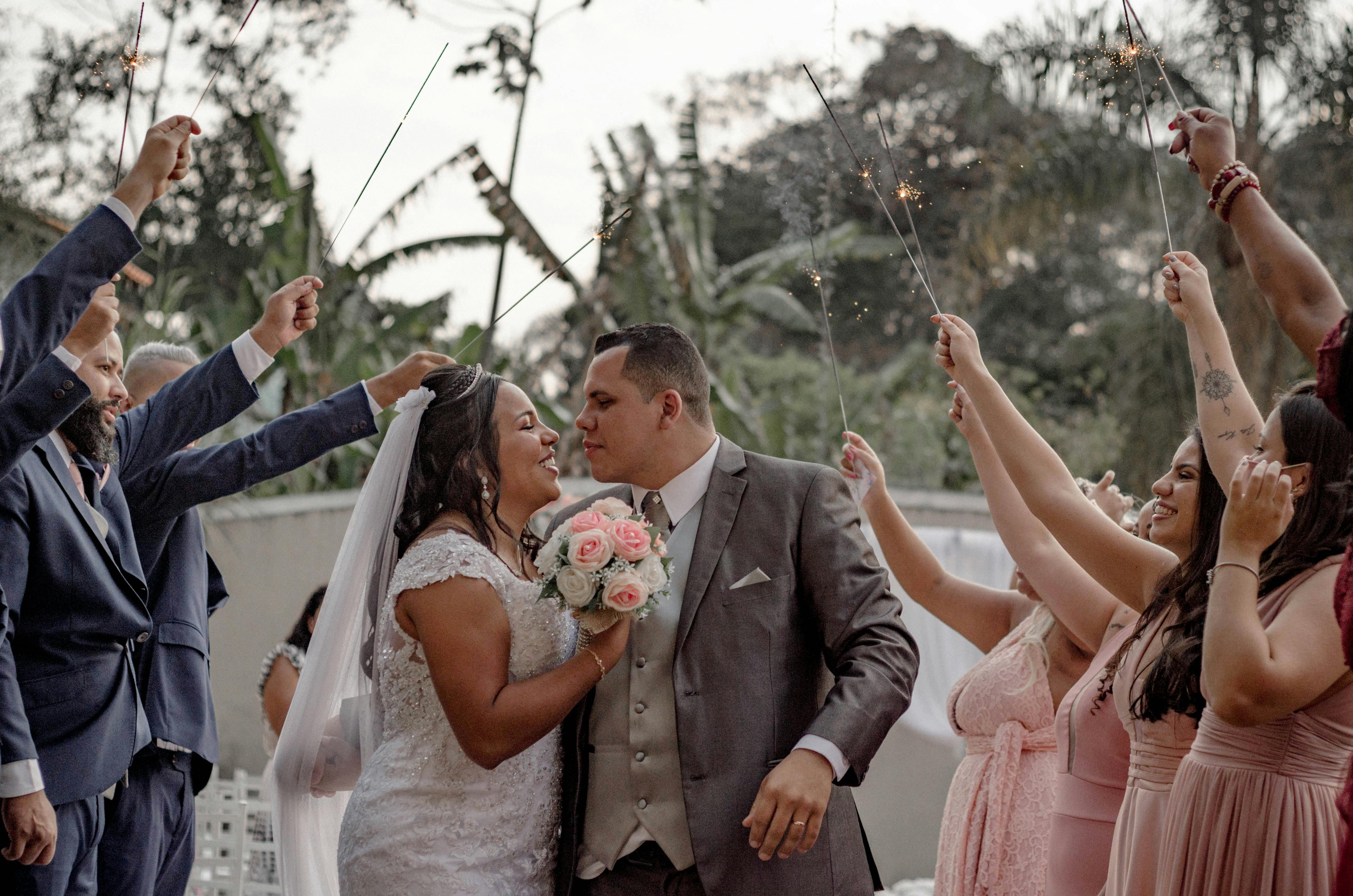 A joyful outdoor wedding featuring a bride and groom surrounded by guests holding sparklers.