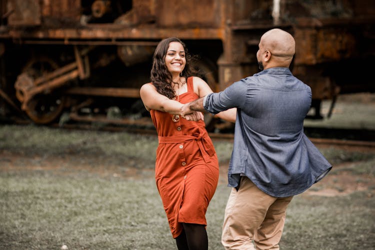 Happy Man And Woman Dancing Holding Hands Outdoors