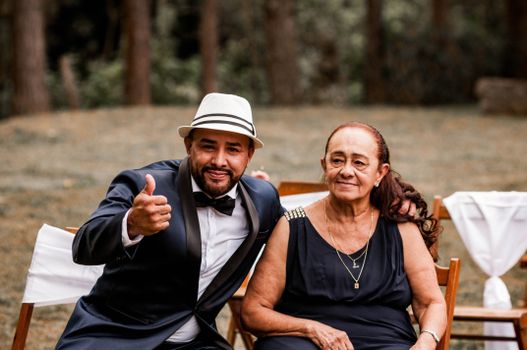 A man in a suit and woman smile at an outdoor event, exuding elegance and joy.