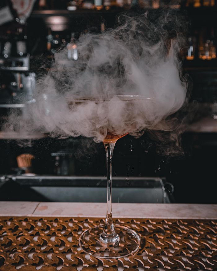 Smoky signature drink glowing on a dimly lit counter